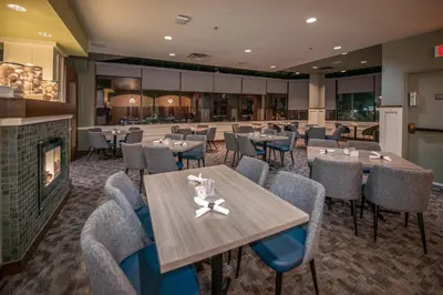 a restaurant with tables and chairs and a fireplace at Coast Bastion Hotel in Nanaimo