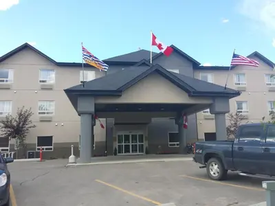 a truck parked in front of a building with flags at Sigma Inn & Suites Hudson's Hope in Hudson Hope