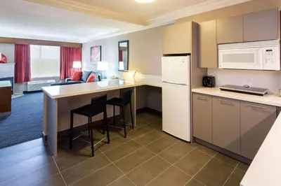 a small kitchen with a counter and a refrigerator at Radisson Hotel & Suites Fort McMurray in Fort McMurray