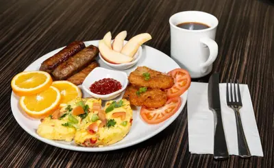 a plate of breakfast food with eggs sausage and tomatoes at Clearwater Suite Hotel in Fort McMurray