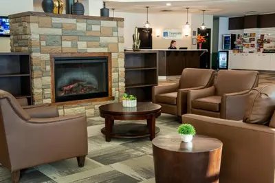 a waiting room with chairs and a fireplace at Clearwater Suite Hotel in Fort McMurray