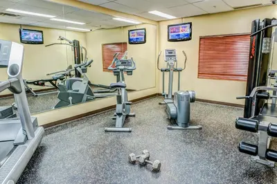 a gym with treadmills and machines in a room at Clearwater Suite Hotel in Fort McMurray