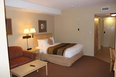 a hotel room with a bed and a chair at Clearwater Suite Hotel in Fort McMurray