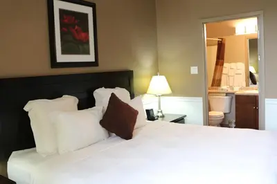 a bedroom with a large white bed with white pillows at Nomad Hotel & Suites in Fort McMurray
