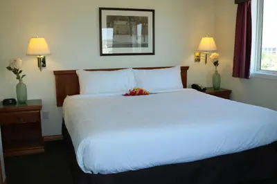 a bedroom with a large white bed with flowers on it at Nomad Hotel & Suites in Fort McMurray