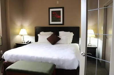 a bedroom with a large bed with white sheets and pillows at Nomad Hotel & Suites in Fort McMurray