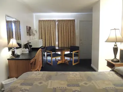 a hotel room with a bed and a table and chairs at 100 Mile Motel & RV Park in One Hundred Mile House