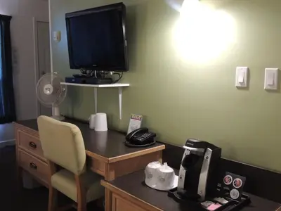 a room with a desk with a television and a chair at 100 Mile Motel & RV Park in One Hundred Mile House