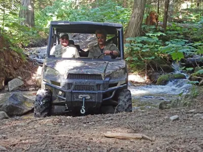 two men in a jeep on a trail in the woods at Mica Mountain Lodge & Log Cabins in Tete Jaune Cache
