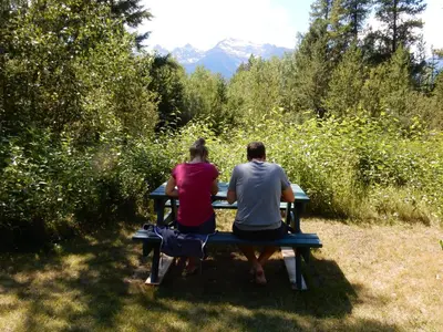 two people sitting on a bench in a park at Mica Mountain Lodge & Log Cabins in Tete Jaune Cache