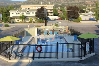 a pool with chairs and umbrellas in a parking lot at Flamingo Motel in Penticton