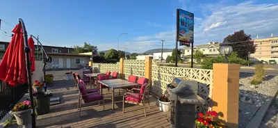 a wooden deck with a table and chairs on it at Flamingo Motel in Penticton