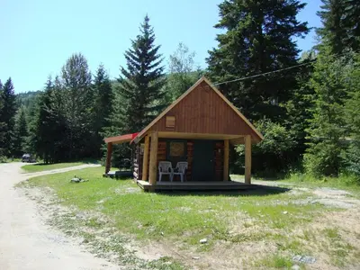 a small cabin with two chairs in front of a road at Helmcken Falls Lodge Cabin Rooms and RV Park in Clearwater