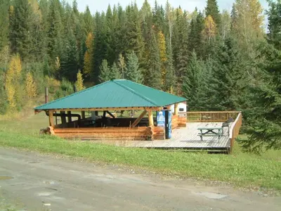 a wooden gazebo with a green roof in a field at Helmcken Falls Lodge Cabin Rooms and RV Park in Clearwater