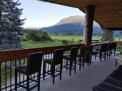 a row of chairs on a porch with a view of a mountain at Harrison Hammond House Farmstay in Harrison Mills
