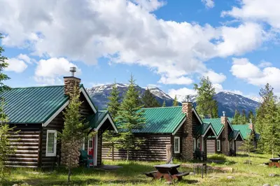 a log cabin with mountains in the background at Pine Bungalows in Jasper