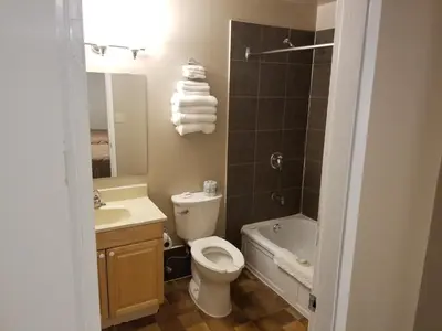 a bathroom with a toilet and a sink and a tub at Apple Tree Inn in Penticton