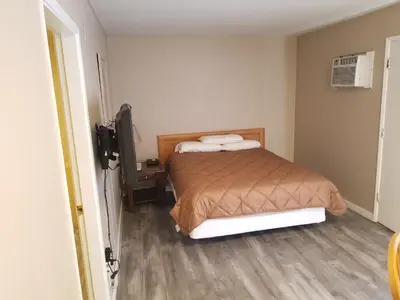 a small bedroom with a bed and a television at Apple Tree Inn in Penticton