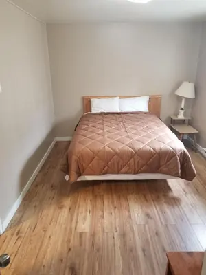 a bedroom with a bed and a wooden floor at Apple Tree Inn in Penticton