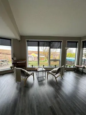 a living room with two chairs and a table and windows at Misty Ridge Retreat B&B in Foothills