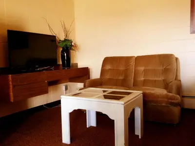 a living room with a chair and a coffee table at Alpine Lodge Motel & Restaurant in Grande Cache