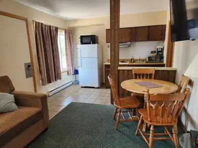 a kitchen and dining room with a table and a refrigerator at Motel Tyrol in Radium Hot Springs