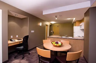 a room with a table and chairs and a kitchen at Woodlands Inn & Suites in Fort Nelson