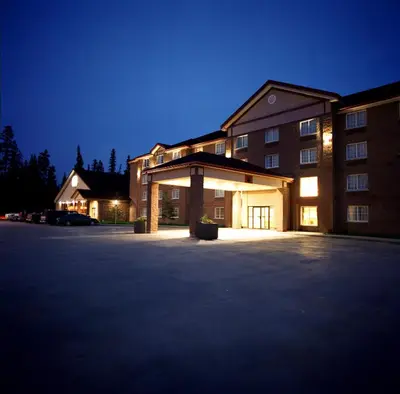a large building with a parking lot at night at Woodlands Inn & Suites in Fort Nelson