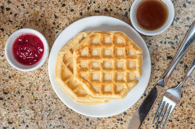 a plate with a waffle on a table with syrup at Days Inn by Wyndham Bonnyville in Bonnyville