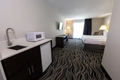 a hotel room with a bed and a kitchen with a microwave at SureStay Hotel by Best Western Castlegar in Castlegar