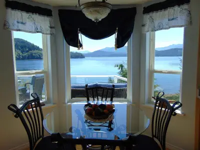 a table with a bowl of fruit on it in front of windows at The Oceanfront Inn on Stephens Bay in Coal Harbour