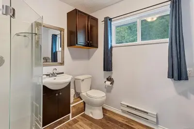 a bathroom with a toilet and a sink and a window at The Oceanfront Inn on Stephens Bay in Coal Harbour
