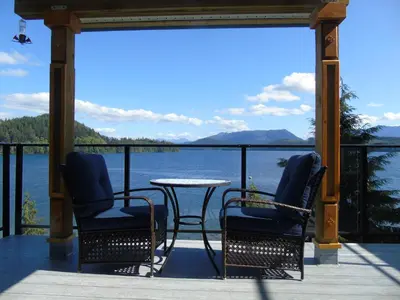 a porch with a table and chairs and a view of the water at The Oceanfront Inn on Stephens Bay in Coal Harbour