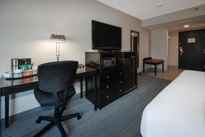 a hotel room with a desk and a bed and a television at Coast Nisku Inn & Conference Centre in Nisku