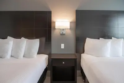 two beds in a hotel room with white pillows at Coast Nisku Inn & Conference Centre in Nisku