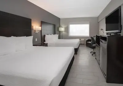 a hotel room with two beds and a flat screen tv at Coast Nisku Inn & Conference Centre in Nisku