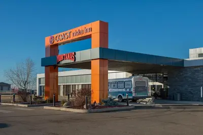 a bus stop in a parking lot with a bus at Coast Nisku Inn & Conference Centre in Nisku