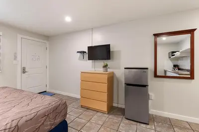 a bedroom with a bed and a refrigerator and a mirror at Oasis Inn in Kelowna