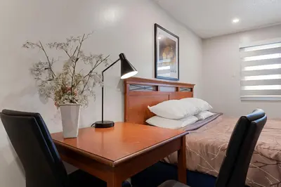 a bedroom with a desk and a bed with a table at Oasis Inn in Kelowna