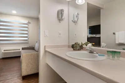 a white bathroom with a sink and a mirror at Oasis Inn in Kelowna