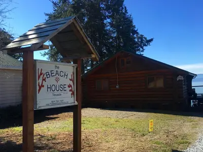 a sign in front of a log house at The Beach House Texada - Gillies Bay Favourite Cabin in Gillies Bay