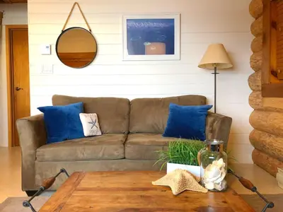 a living room with a brown couch and blue pillows at The Beach House Texada - Gillies Bay Favourite Cabin in Gillies Bay
