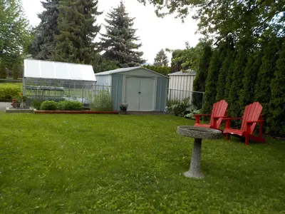 two red chairs sitting on a bench in a yard at Dogwood Bed & Breakfast in Summerland