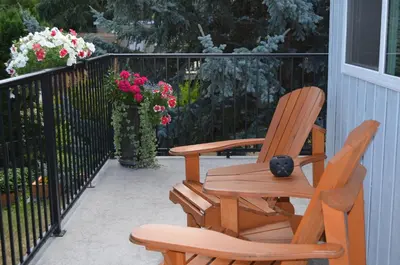 two chairs and a table on a porch with flowers at Dogwood Bed & Breakfast in Summerland