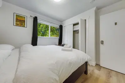 a white bedroom with a large bed and a window at Quite House near the Vancouver Airport in Richmond