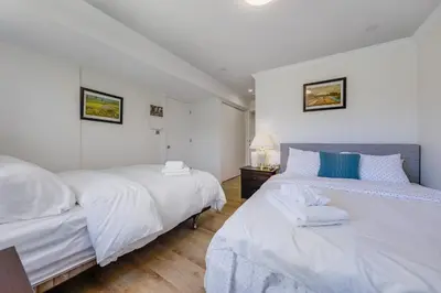 two beds in a bedroom with white walls and wood floors at Quite House near the Vancouver Airport in Richmond