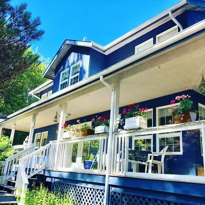 a blue house with potted plants on the front porch at Seafarer Bed & Breakfast in Tofino
