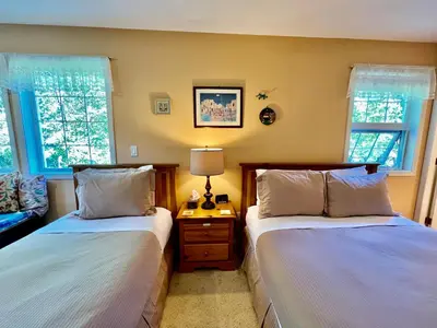 two beds in a room with two windows at Seafarer Bed & Breakfast in Tofino