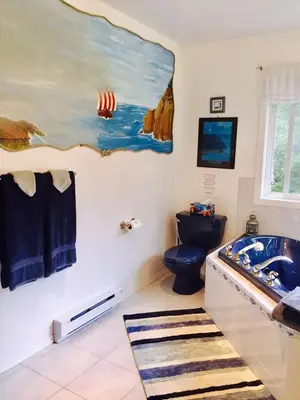 a bathroom with a blue toilet and a painting on the wall at Seafarer Bed & Breakfast in Tofino