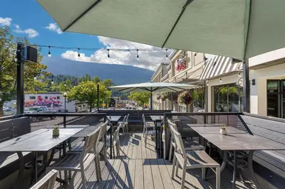 a row of tables and chairs with umbrellas on a patio at Best Western Plus Baker Street Inn in Nelson
